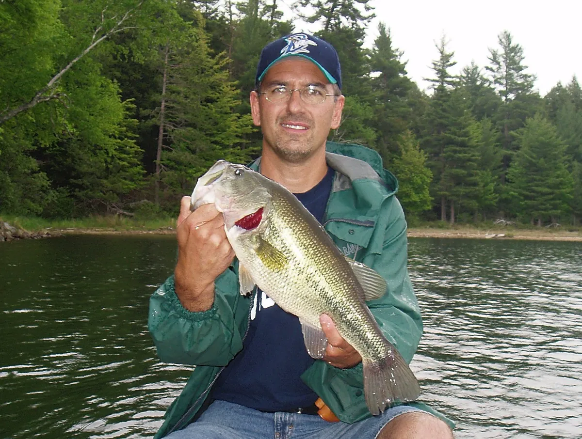 An angler holding a largemouth bass on a lake
